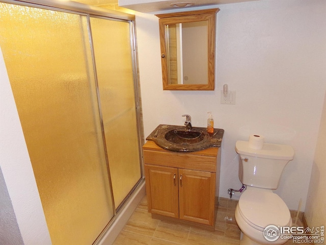 bathroom with vanity, a shower stall, and toilet