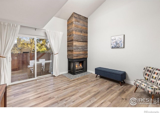 sitting room with a tiled fireplace, baseboards, lofted ceiling, and wood finished floors