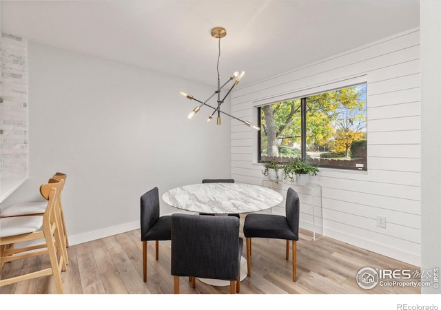 dining room with baseboards, light wood-type flooring, and an inviting chandelier