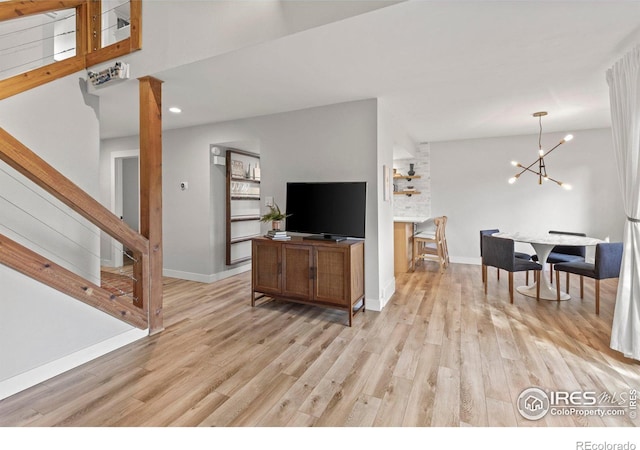 living area featuring light wood finished floors, baseboards, a chandelier, stairs, and recessed lighting