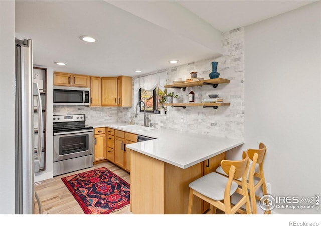 kitchen with a peninsula, backsplash, appliances with stainless steel finishes, and a sink