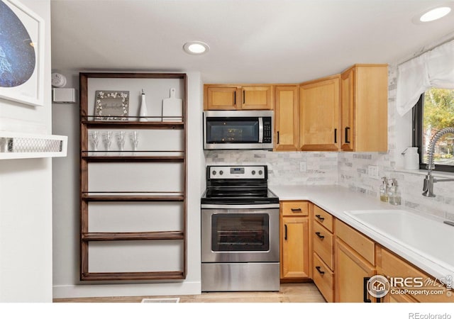 kitchen featuring visible vents, a sink, backsplash, stainless steel appliances, and light countertops