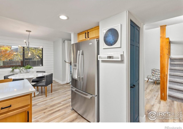 kitchen with light wood-style flooring, recessed lighting, hanging light fixtures, light countertops, and stainless steel fridge