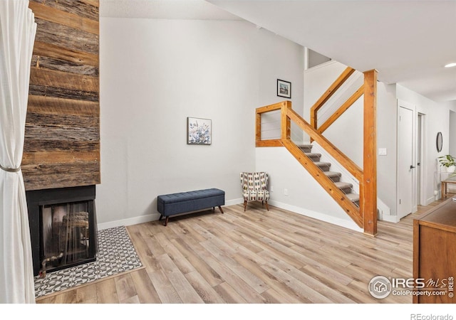 sitting room featuring a tiled fireplace, stairs, wood finished floors, and baseboards