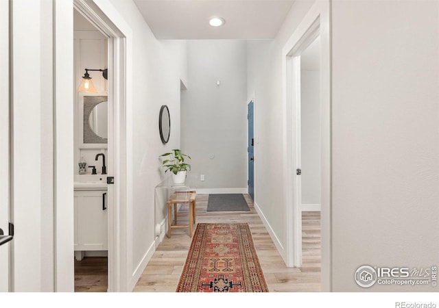 interior space featuring recessed lighting, light wood-style flooring, baseboards, and a sink