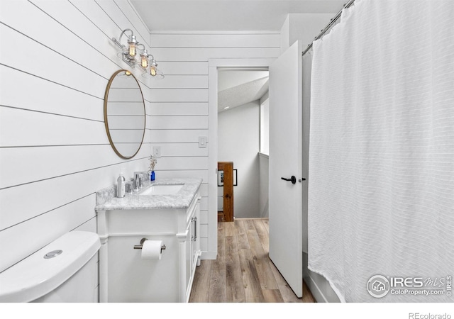 full bathroom with wooden walls, toilet, vanity, and wood finished floors