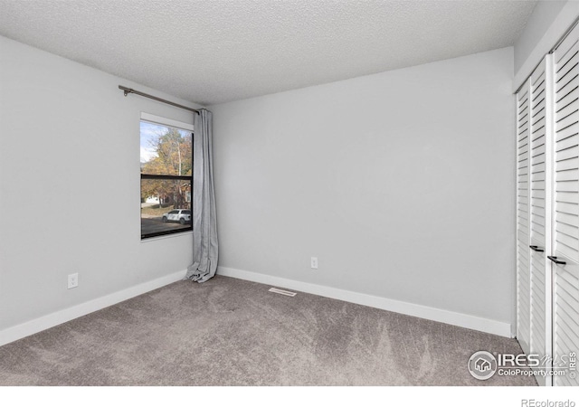 empty room with visible vents, a textured ceiling, baseboards, and carpet floors