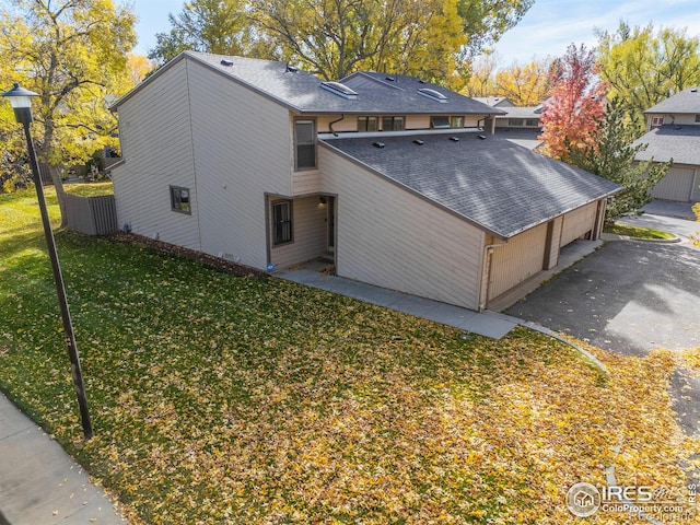 view of home's exterior featuring a garage, a shingled roof, and a yard