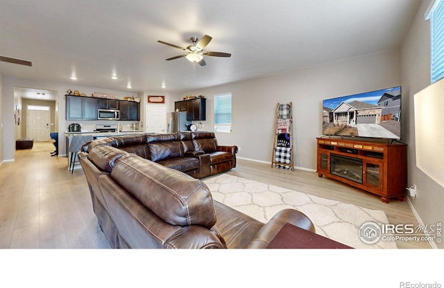 living room with visible vents, a ceiling fan, light wood-type flooring, and baseboards