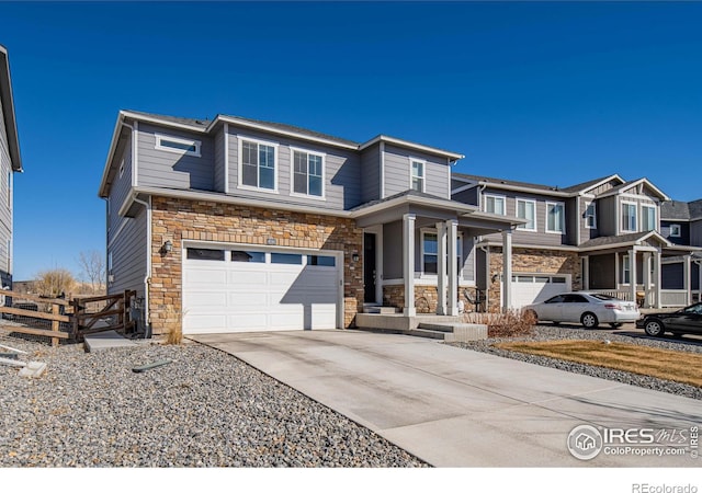 prairie-style house featuring stone siding, concrete driveway, a garage, and fence