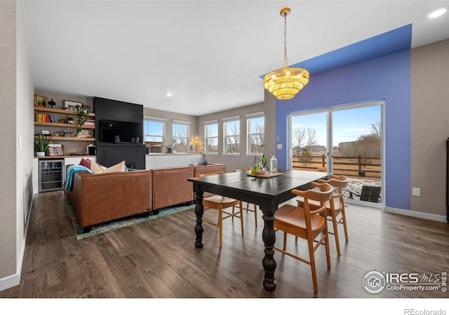 dining space with recessed lighting, wine cooler, wood finished floors, and a notable chandelier