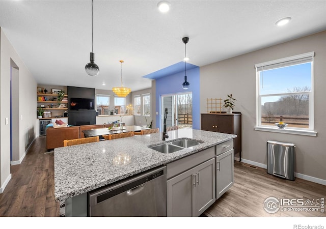 kitchen with a sink, baseboards, light stone countertops, and dishwasher