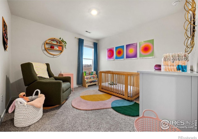 carpeted bedroom with baseboards, visible vents, and a crib