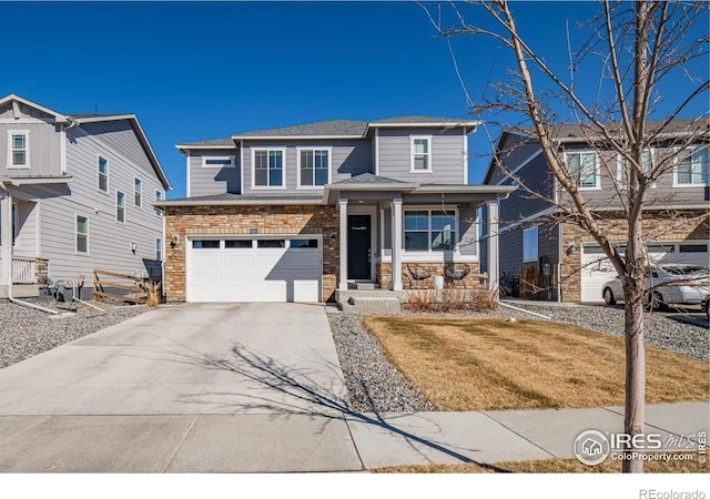 traditional-style home featuring a porch, driveway, a front yard, an attached garage, and stone siding