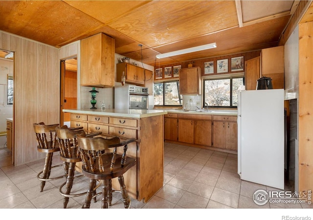 224 Loveland Heights Ln, Drake, CO 80515 - kitchen featuring brown cabinetry, freestanding refrigerator, light countertops, wall oven, and wood walls