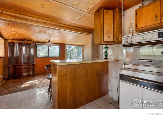 224 Loveland Heights Ln, Drake, CO 80515 - kitchen with tile patterned flooring, backsplash, oven, a peninsula, and brown cabinetry