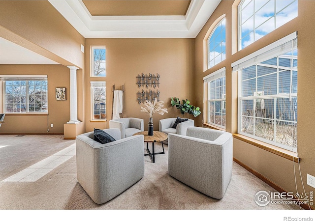 living room featuring a wealth of natural light, decorative columns, carpet floors, and baseboards