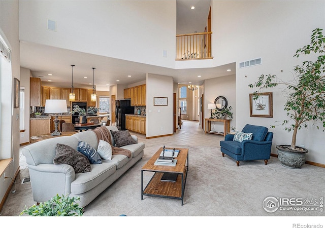 living area featuring baseboards, visible vents, an inviting chandelier, a high ceiling, and recessed lighting