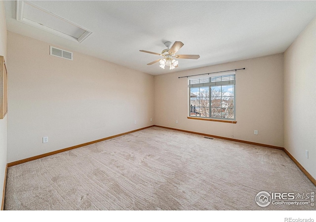 spare room featuring visible vents, carpet, baseboards, attic access, and ceiling fan