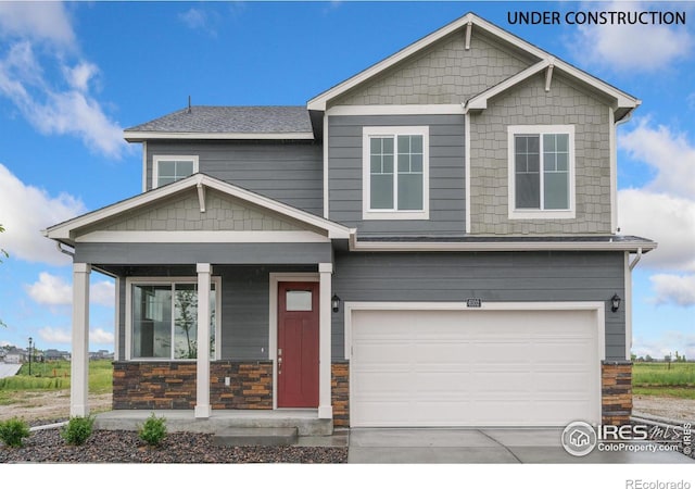 craftsman-style house with driveway, an attached garage, covered porch, and stone siding