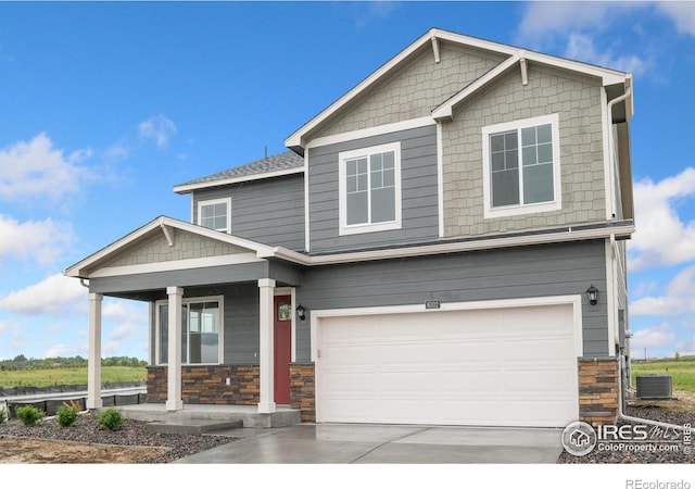 craftsman house with central air condition unit, driveway, stone siding, covered porch, and a garage