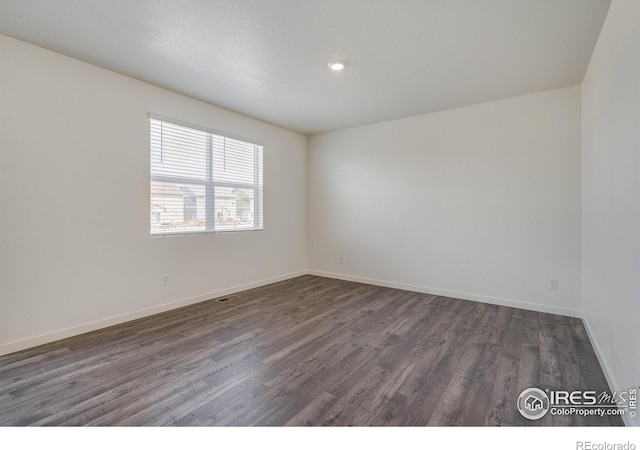 unfurnished room with visible vents, baseboards, and dark wood-style flooring