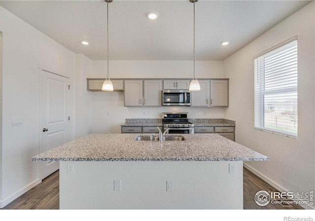 kitchen featuring gray cabinetry, a sink, light stone counters, dark wood-style floors, and stainless steel appliances