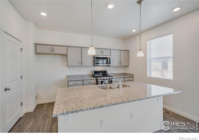 kitchen featuring light stone countertops, dark wood finished floors, gray cabinets, stainless steel appliances, and a sink