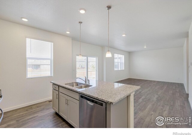 kitchen with a sink, light stone counters, wood finished floors, dishwasher, and hanging light fixtures