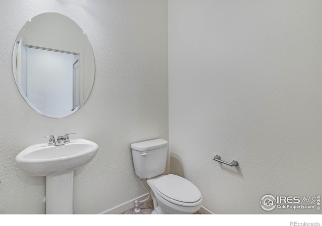 half bath with a sink, baseboards, and toilet