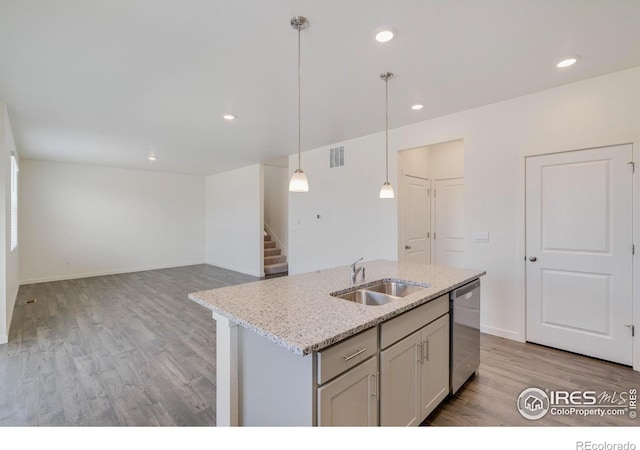 kitchen with light wood-type flooring, a sink, decorative light fixtures, light stone countertops, and dishwasher