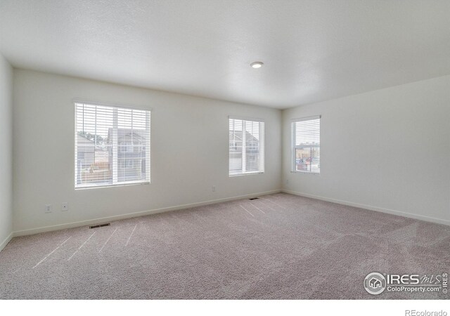 unfurnished room with visible vents, baseboards, and light carpet