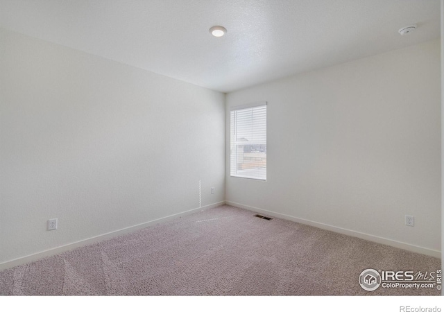 spare room featuring baseboards, visible vents, and light carpet