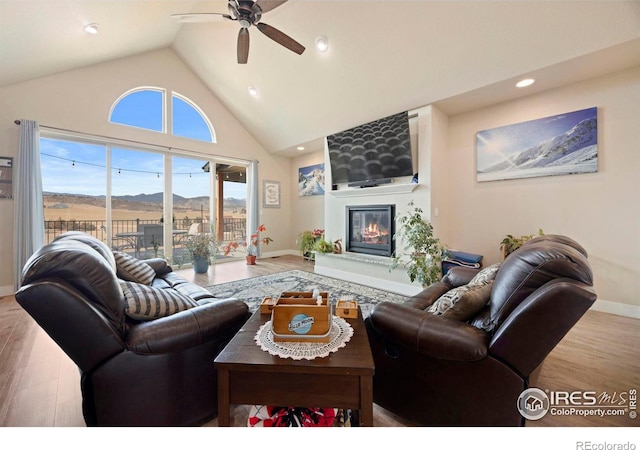 living room with high vaulted ceiling, wood finished floors, recessed lighting, a fireplace, and baseboards