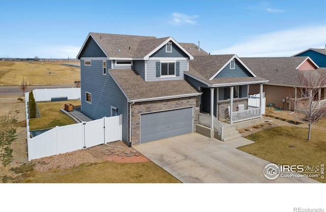 view of front of house with fence, concrete driveway, covered porch, a garage, and a gate