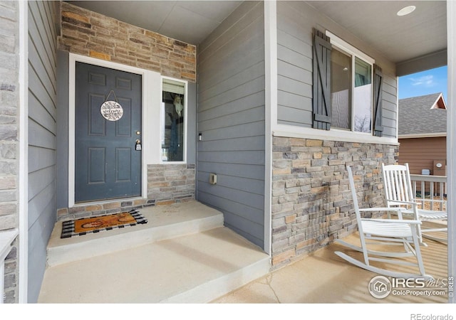 view of exterior entry with a porch and stone siding