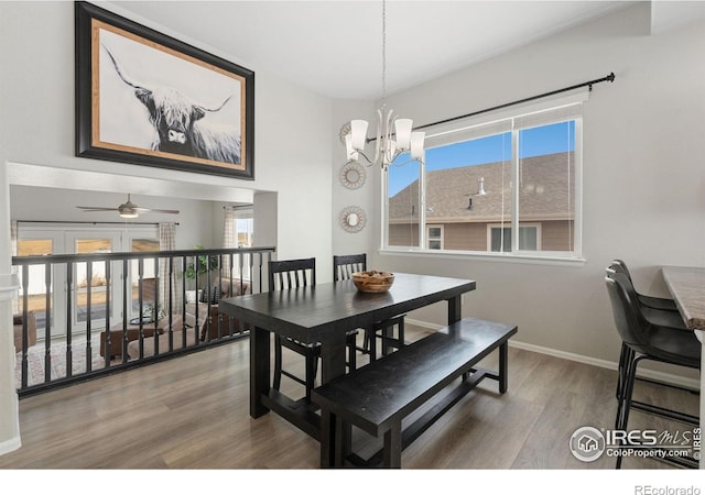 dining room with ceiling fan with notable chandelier, baseboards, and wood finished floors