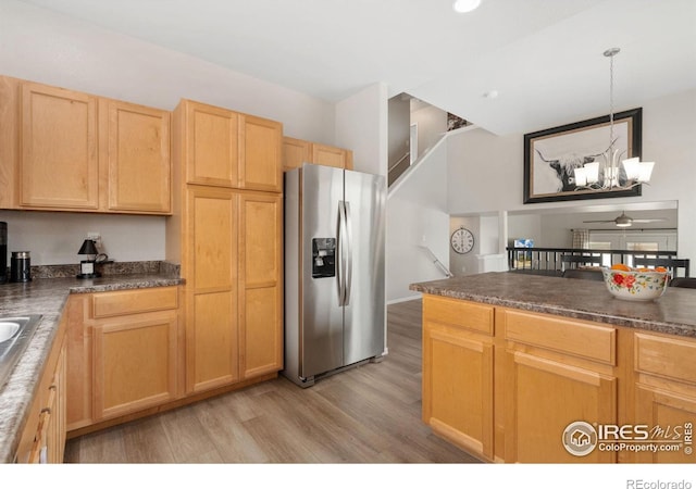 kitchen featuring stainless steel fridge, dark countertops, light wood-style flooring, and ceiling fan with notable chandelier