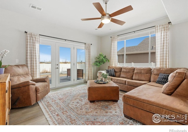 living room featuring ceiling fan, visible vents, light wood-style flooring, and french doors