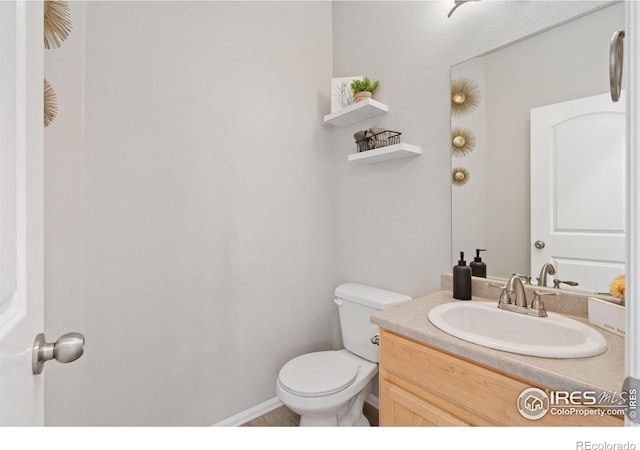 half bath with toilet, vanity, and baseboards