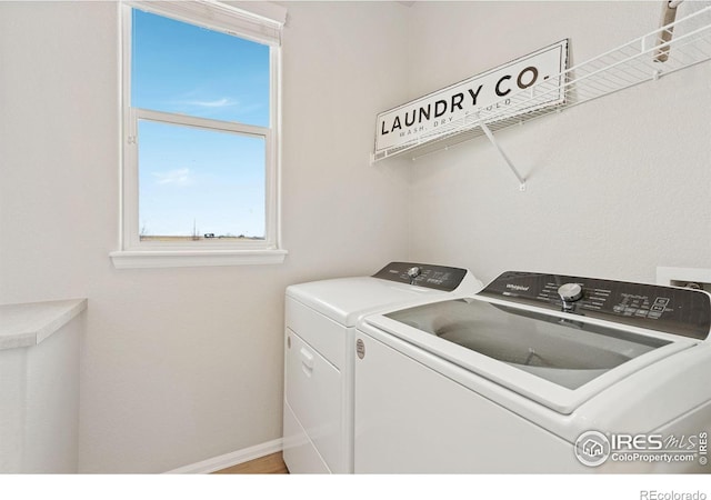 clothes washing area with laundry area, separate washer and dryer, and baseboards