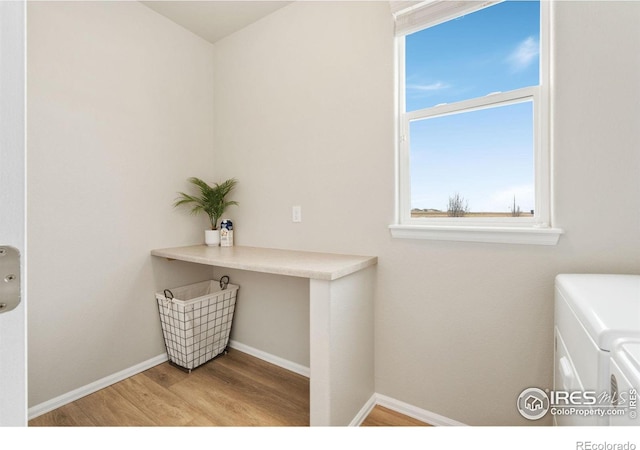 interior space featuring washer and clothes dryer, laundry area, light wood-style flooring, and baseboards