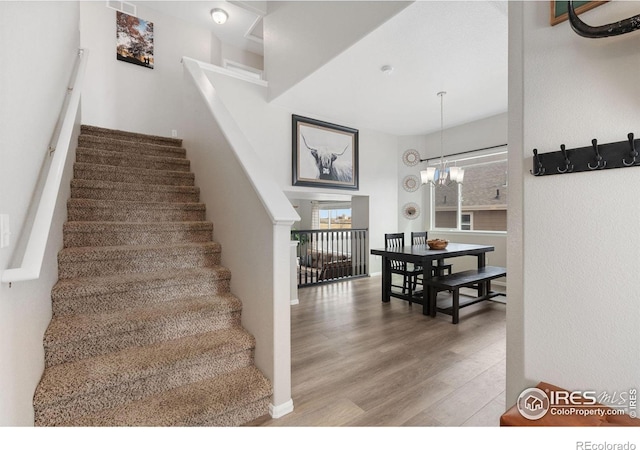 staircase featuring an inviting chandelier and wood finished floors