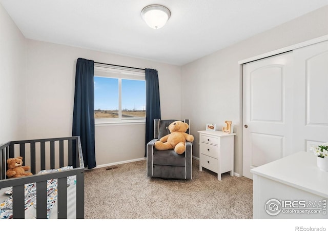 bedroom with baseboards, a crib, light colored carpet, and a closet