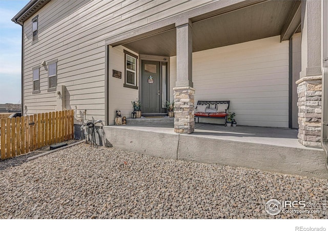 view of exterior entry featuring a porch and fence