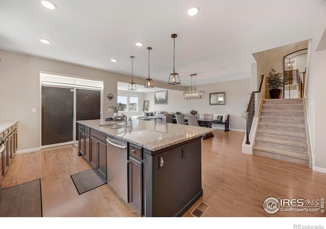 kitchen with visible vents, decorative light fixtures, light wood-type flooring, stainless steel dishwasher, and a sink