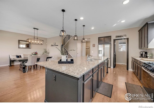 kitchen featuring light wood finished floors, a kitchen island with sink, stainless steel fridge with ice dispenser, recessed lighting, and a sink