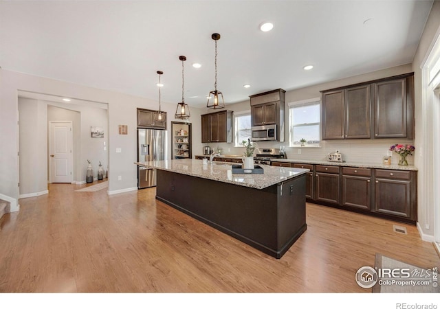 kitchen featuring dark brown cabinetry, light wood-style flooring, a kitchen island with sink, and stainless steel appliances