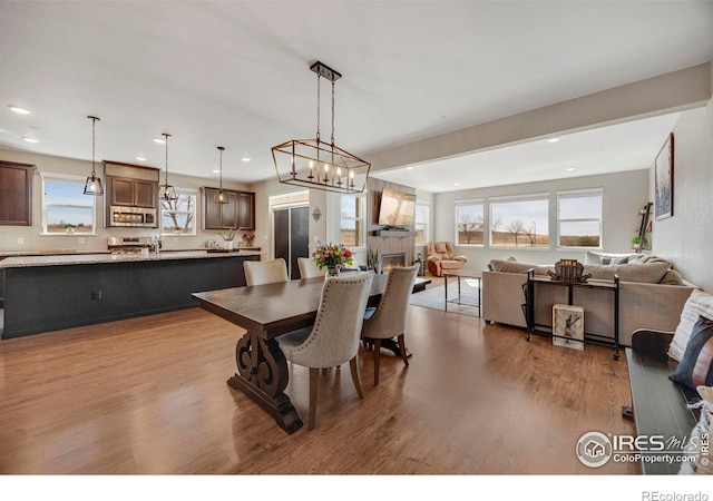 dining space with recessed lighting, wood finished floors, and a large fireplace