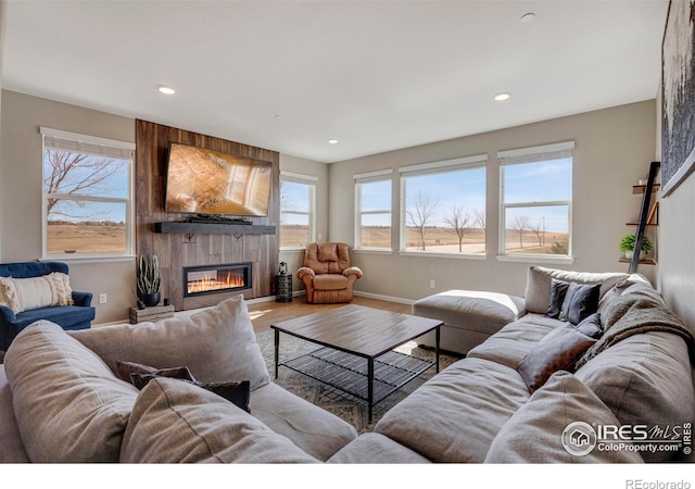 living room featuring wood finished floors, recessed lighting, a healthy amount of sunlight, and a large fireplace